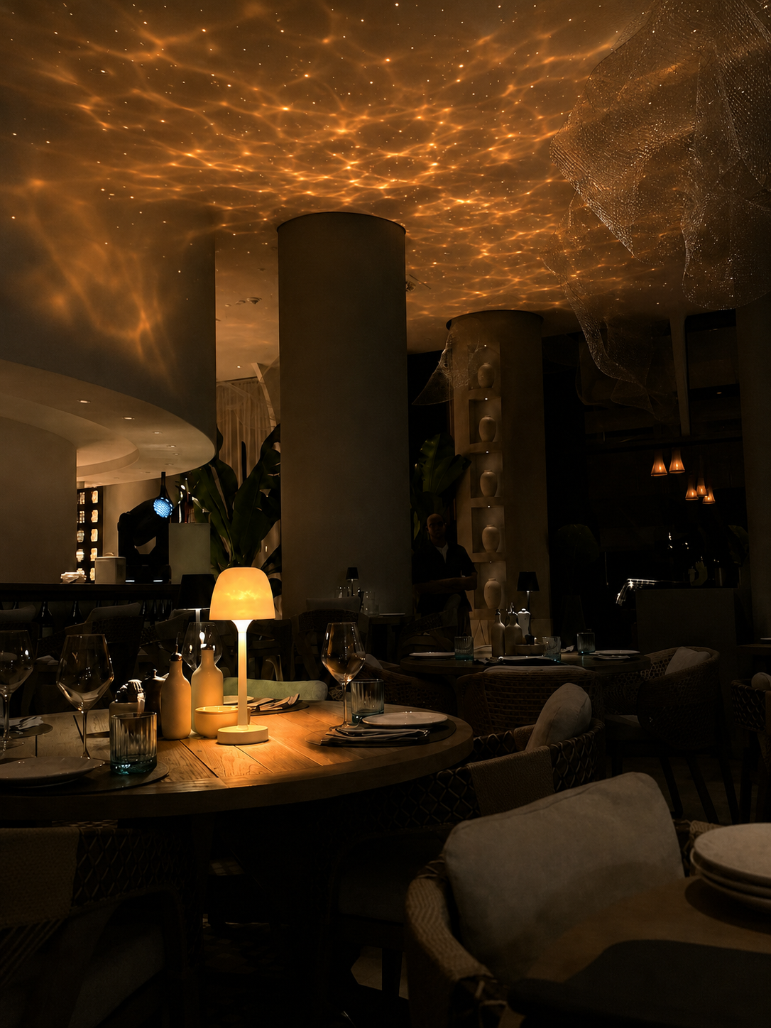 LYNOVAIR ONE posée sur une table de restaurant, projetant un ciel étoilé ambré au plafond